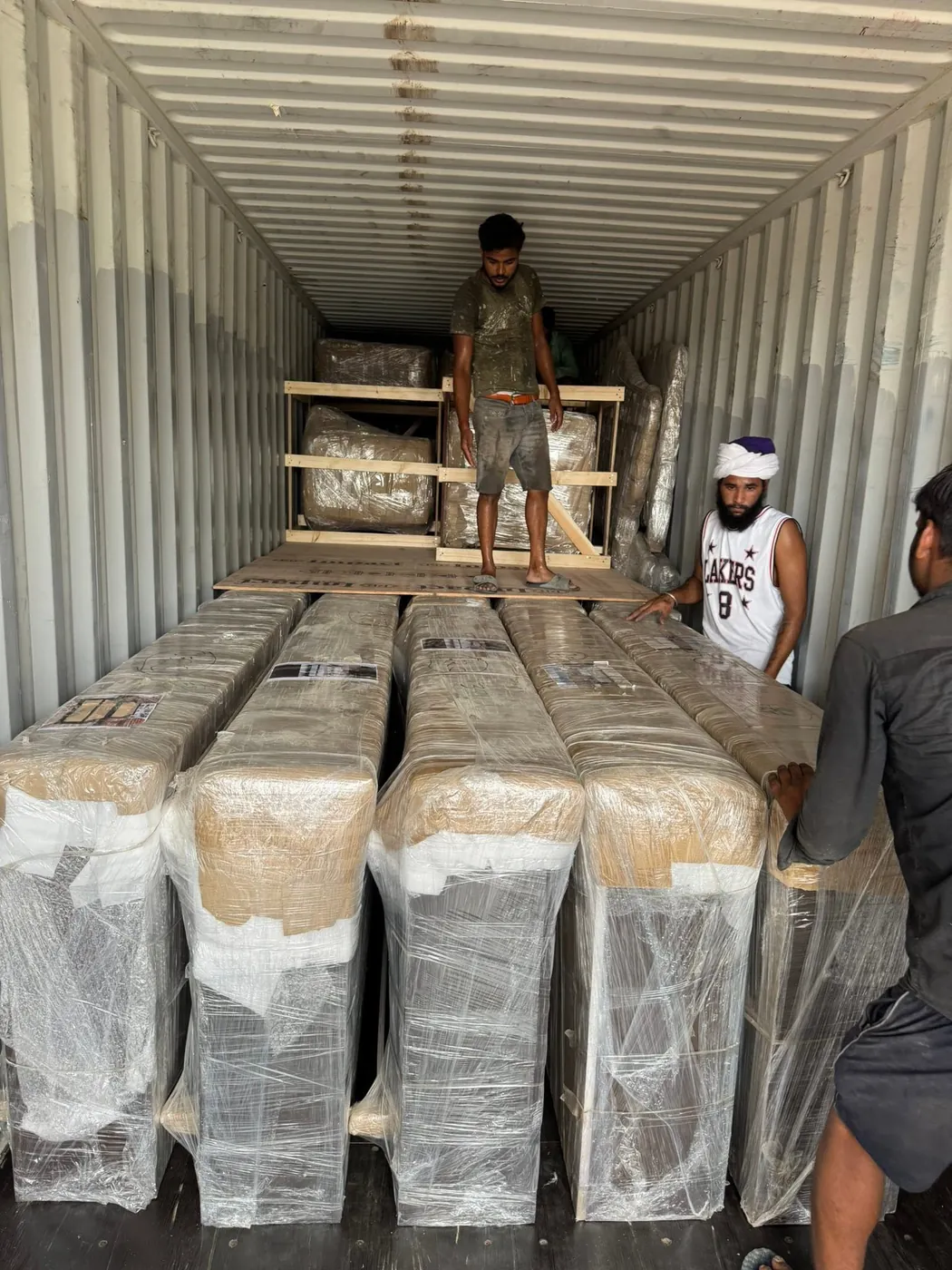 Shrink-wrapped furniture being stuffed into a shipping container for export